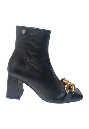 Bottine en cuir noir avec talon bloc, bout pointu et chaîne dorée décorative à l'avant.