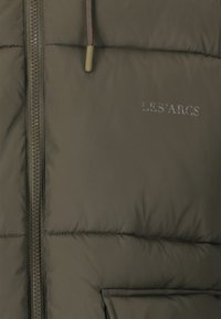 Mørke olivenfarvet polstret vest med frontlynlås, der har et subtilt præget logo "LES'ARCS" og struktureret stof finish.