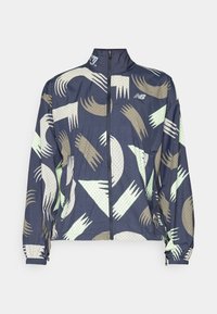 Granatowa kurtka zapinana na zamek z geometrycznymi wzorami w kolorze kremowym i zielonym, z kołnierzem typu stójka i elastycznymi mankietami, wykonana z lekkiego materiału.