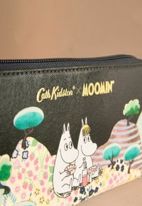 Čierna zipsová taštička s postavičkami Moomin na vzorovanej krajine. Materiál vyzerá textúrovane, s lesklým povrchom. Viditeľné zlaté logo.