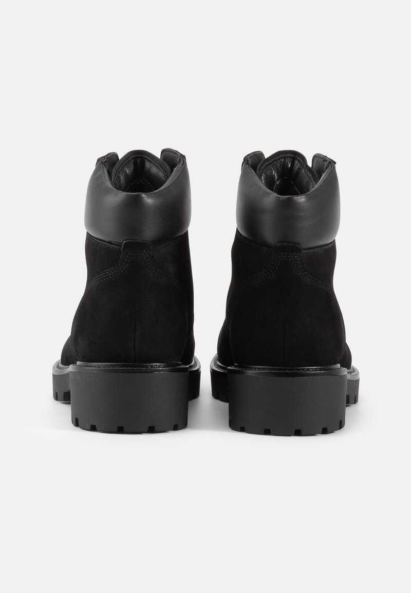 Zwarte leren enkelboot met een glad bovenwerk en een gewatteerde kraag, voorzien van een dikke rubberen zool voor verbeterde grip en duurzaamheid.