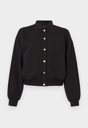 Giacca corta nera in misto cotone, con colletto alto, bottoni a pressione dorati e due tasche frontali con polsini elasticizzati.