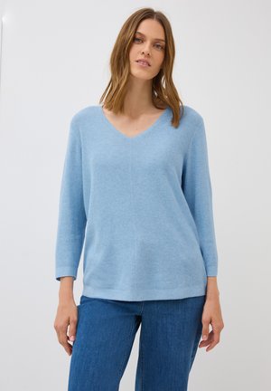 Pull bleu clair en V avec un motif de tricot texturé, manches trois-quarts et coupe décontractée, associé à un jean en denim bleu.