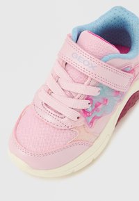 Sapatilha rosa com materiais em rede e couro, apresentando um design decorativo colorido, tira de velcro e sola de borracha com padrões texturizados.