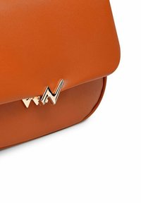 Oranžová kožená kabelka s zakřiveným designem, hladkým povrchem a kovovým klipem ve tvaru zig-zag na přední straně.