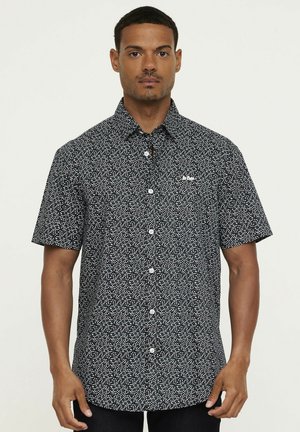 Chemise à manches courtes boutonnée en bleu marine foncé avec un motif à pois blancs, dotée d'un col classique et de boutons à l'avant.