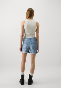 Ljust grå ribbad linne topp i kombination med ljusblå uppvikta denimshorts. Svarta ankelstövlar med remmar och vita crew-strumpor. Enkel design.