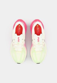 Baskets de sport blanches avec des accents roses, tige en mesh et semelle texturée. Présente des semelles intérieures rouges et un design de laçage minimaliste.