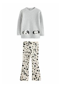 Maglione grigio lavorato a maglia con facce di cane sulle tasche, abbinato a pantaloni crema con macchie nere e orli svasati.
