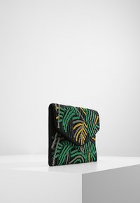 Clutchväska i svart tyg, med intrikata mönster av gröna, gula och beigea pärlor som liknar lövverk. Design med vik och textur.