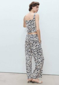 Floral printed crop top and wide-leg pants in navy blue and cream. The top has a square back and adjustable tie detail, smooth fabric texture.