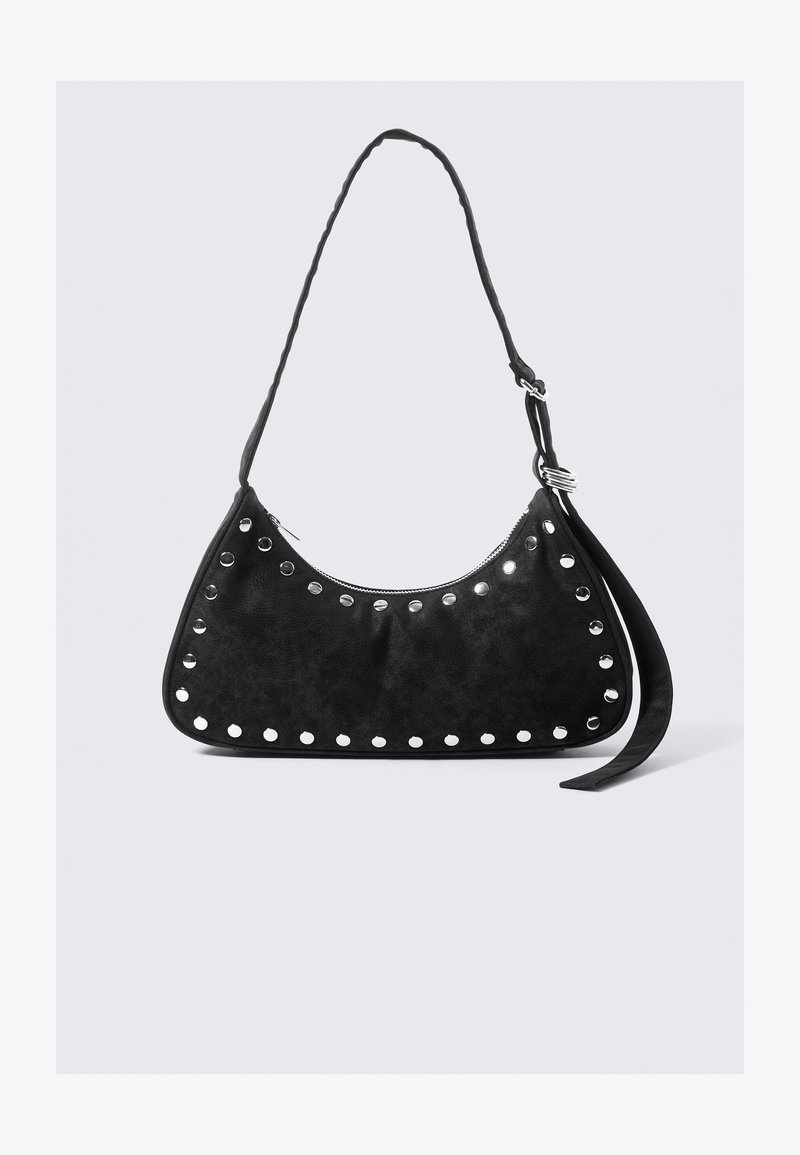 Sac à main en simili cuir noir avec une forme incurvée, rehaussé de clous en métal circulaires le long du bord, doté d'une fermeture éclair et d'une longue bandoulière.
