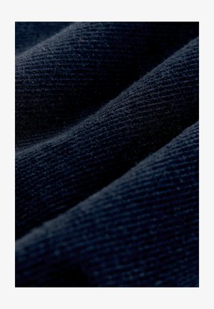 Tumes tekstureeritud kangas ribadega mustriga, omades pehmet, kudumise välimust. Materjal näitab kergeid erinevusi kudumise tiheduses.