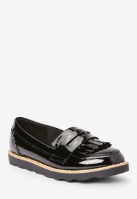 Svarta lackläderloafers med fransdetaljer, rund tå och en strukturerad svart gummisula med ljusbeige kant.