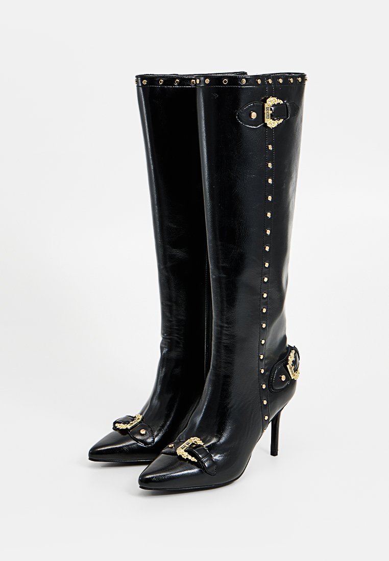 Czarne skórzane botki do kolan z ostrymi czubkami, złotymi ćwiekami i dekoracyjnymi złotymi klamrami z przodu i po bokach, z obcasami w szpilce.
