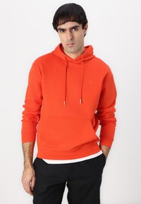 Bright orange hoodie with a kangaroo pocket and drawstring hood. Features a subtle logo on the chest and long, fitted sleeves.