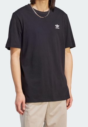 T-shirt nera in cotone con maniche corte, caratterizzata da un logo adidas bianco sul petto. Tessuto liscio, vestibilità comoda e design con colletto tondo.