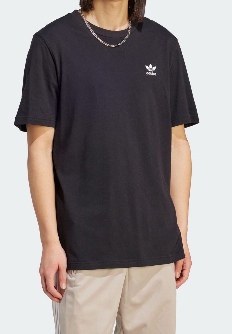 Camiseta de algodón negra de manga corta, con un logo blanco de adidas en el pecho. Textura suave, corte relajado y diseño de cuello redondo.