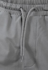 Grijze joggerbroek met een elastische tailleband, verstelbaar trekkoord en een gladde textuur. Beschikt over een zijzak en nette stiksels.