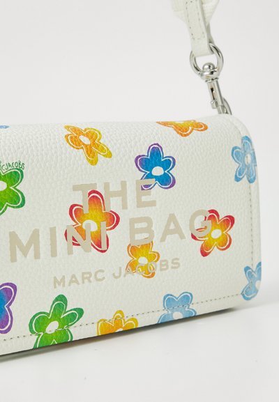 White leather mini bag with colorful flower print. Features gold text "THE MINI BAG" and "MARC JACOBS." Includes a detachable strap.