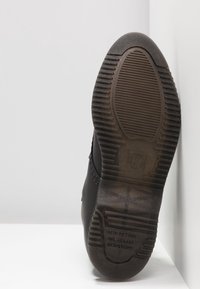 Semelle de botte noire avec motif de semelle et texte indiquant une résistance aux acides, à l'essence, à l'huile et aux alcalis.