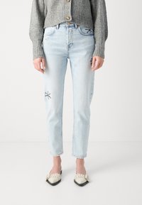 Lys blå høyt liv jeans med rett snitt, med blomsterbroderi og slitte detaljer. Kombinert med en grå, ribbet cardigan.