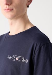 Navyblaue Baumwoll-T-Shirt mit Rundhals, kurzen Ärmeln und einem bedruckten Logo mit "GANT 1949" und "NEW HAVEN CONNECTICUT."
