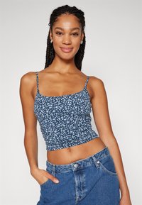 Top cropped azul floral com alças finas, textura franzida e design ajustado. Usado com calções de ganga de cintura alta, com um bolso.