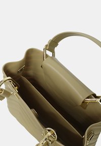 Borsa beige con un bordo superiore ondulato, accessori d'oro e un interno aperto che presenta un compartimento centrale e una texture liscia.