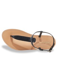 Sandalo infradito in pelle nera con suola piatta color tan, cinturino alla caviglia regolabile e dettagli di cucitura sottili. Logo stampato sulla soletta.