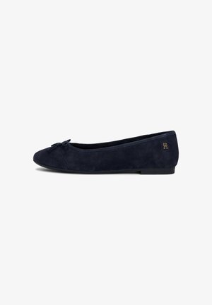 Ballerine en daim bleu marine avec bout arrondi, petit nœud décoratif, talon bas et logo de marque métallique près du talon.