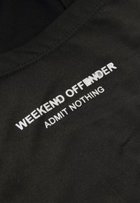 Zwarte katoenen sweatshirt met witte tekst "WEEKEND OFFENDER" en "ADMIT NOTHING" in een vet, modern lettertype. Zachte textuur.