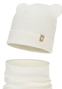 White ribbed knit beanie with bear ears and matching neck warmer. Features a small heart logo on a fabric tag. Soft texture.