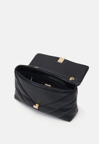 Svart läderhandväska med quiltad design, guldhårdvarulås och innerficka. Öppen med en mjuk finish och strukturerad form.