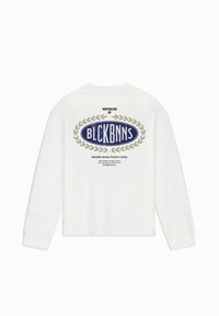 Witte langarmshirt met een blauw ovaal logo, versierd met gouden laurieraccenten en tekst. Het kledingstuk heeft een ontspannen pasvorm en een ronde halslijn.