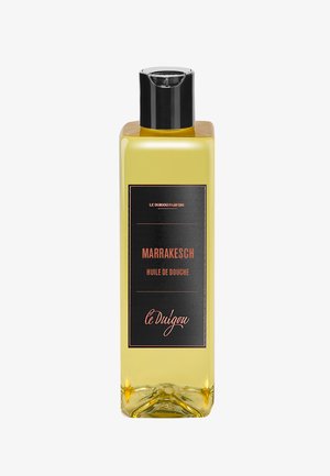 Transparente Flasche mit gelbem Duschöl und schwarzem Deckel. Das Etikett auf der Vorderseite zeigt einen schwarzen Hintergrund und orangefarbene Schrift mit der Aufschrift "Marrakesch Huile de Douche."