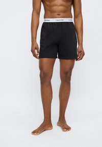 Μαύρα βαμβακερά μποξεράκια με ελαστική λευκή μέση που φέρει το λογότυπο «Calvin Klein». Απλός σχεδιασμός με άνετη εφαρμογή.