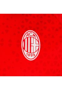 Maglia da calcio rossa con un motivo testurizzato a piccoli triangoli. Il logo centrale mostra "ACM 1899" all'interno di un badge bianco ovale.
