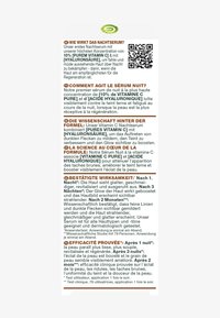 Nattserumförpackning med vit bakgrund, grön logotyp, svart och färgglad text på flera språk, innehåller en QR-kod för mer information.