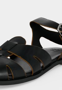 Μαύρο δερμάτινο ανδρικό σανδάλι με ανοιχτά δάχτυλα, σχέδιο με λωρίδες και ρυθμιζόμενο ασημένιο κούμπωμα στο λουράκι του αστραγάλου.