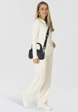Top bianco a costine a maniche lunghe, pantaloni a gamba larga color crema, borsa nera con texture e manici corti, e sneakers bianche.