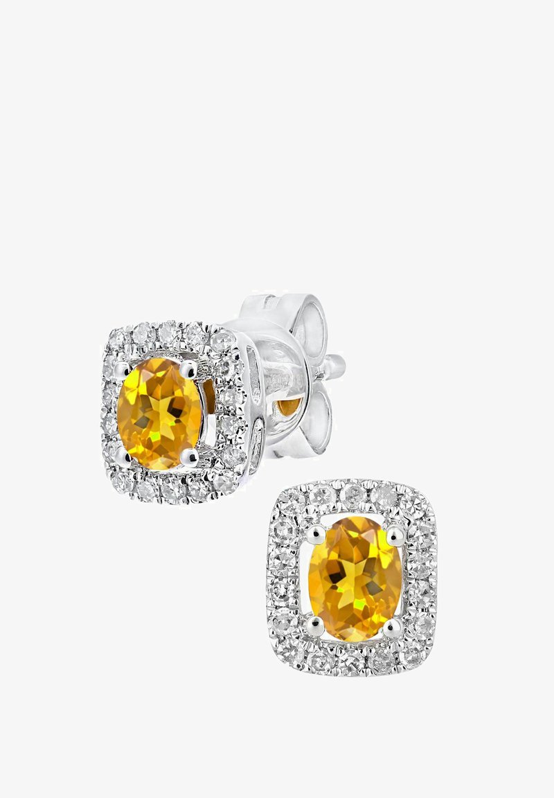 Na uchu sú náušnice z kubického zirkónu so strede žltým oválnym kameňom obkoleseným halo z čírych kameňov, umiestnené v striebornom kovovom ráme so štvorcovým dizajnom.