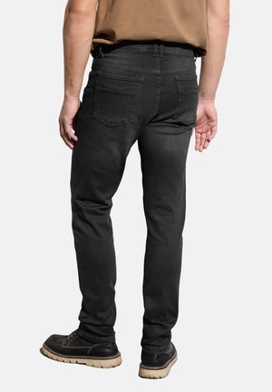 Mustat farkut slim fit -mallilla, joissa on keskitason vyötärö, kaksi takataskua ja ompeluyksityiskohtia, yhdistettynä tummaan jalkaan.