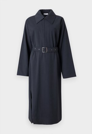 Tumesinine kleit kraega kaelusega, pikkade varrukatega ja vööga vöökohal. Omaduseks on sirge lõige külgmistest lõhikestega, mis võimaldavad liikumist hõlbustada.