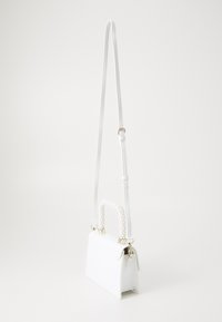 Biała torba na ramię z ekologicznej skóry, z teksturowanym uchwytem ozdobionym perłami, regulowanym paskiem oraz złotymi elementami ozdobnymi. Kompaktowy, prostokątny kształt.