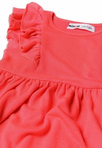Koraalrode jurk met rimpelige schouders, textuurstof en een gathered taille, wat zorgt voor een vloeiende silhouet en een zachte uitstraling.