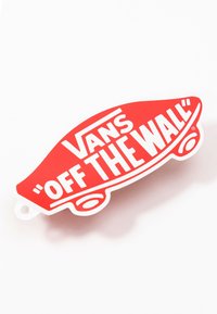 Roter Skateboard-förmiger Aufnäher mit dem Schriftzug "VANS" und "OFF THE WALL" in fettem Weiß, mit Schlaufe zum Befestigen. Glatte Oberfläche.