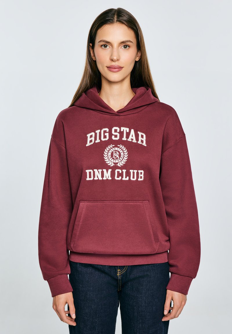 Felpa bordeaux con una grande grafica bianca "BIG STAR DNM CLUB". Presenta una tasca a marsupio, cappuccio con cordino e polsini a coste.