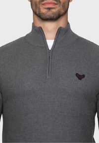 Maglione grigio lavorato a maglia con collo con zip, caratterizzato da un motivo testurizzato e un piccolo logo ricamato sul lato sinistro del petto.