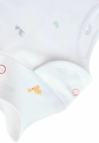 Biele bavlnené detské body s malými zvieracími vzormi v rôznych farbách. Obsahuje jemné okraje a štítok s červeným kruhovým dizajnom.